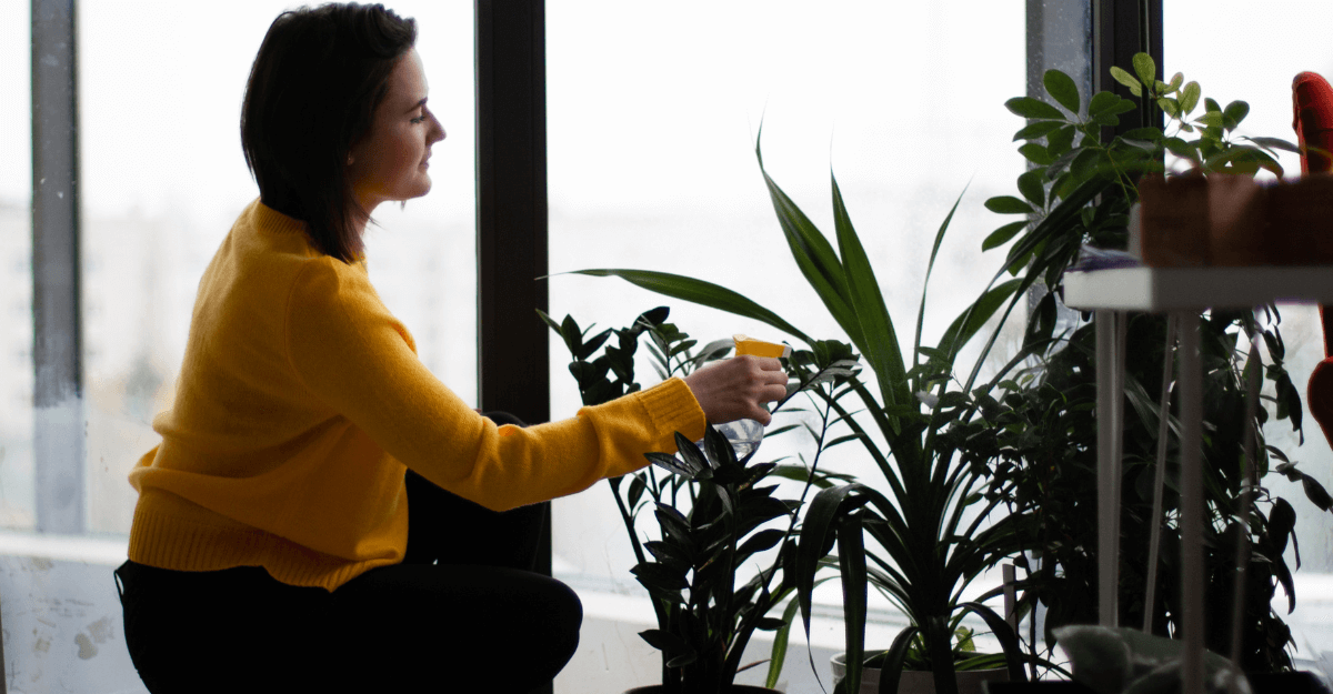 woman watering plants with spray bottle