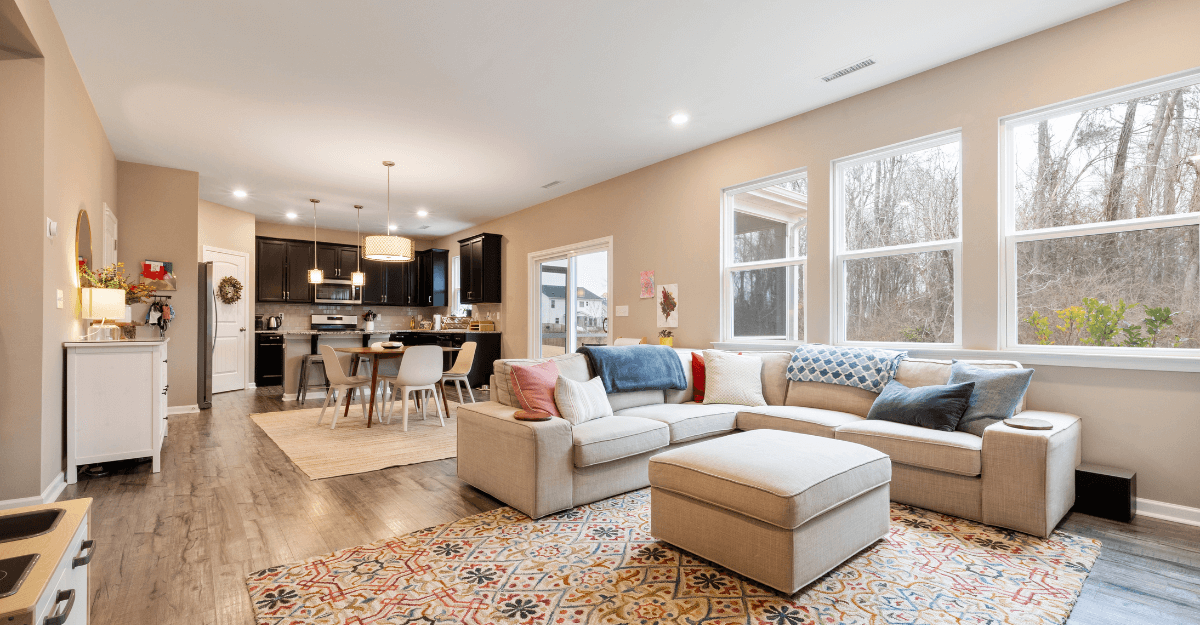 living room with beige sofa and chair with kitchen in the back